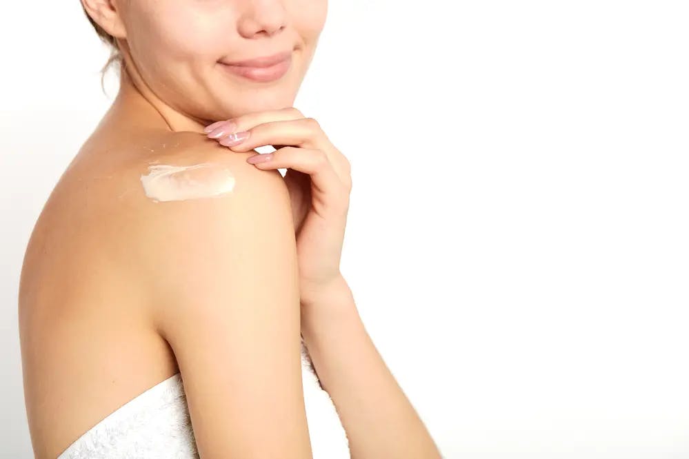Cover Image for A woman applying cream to her shoulder